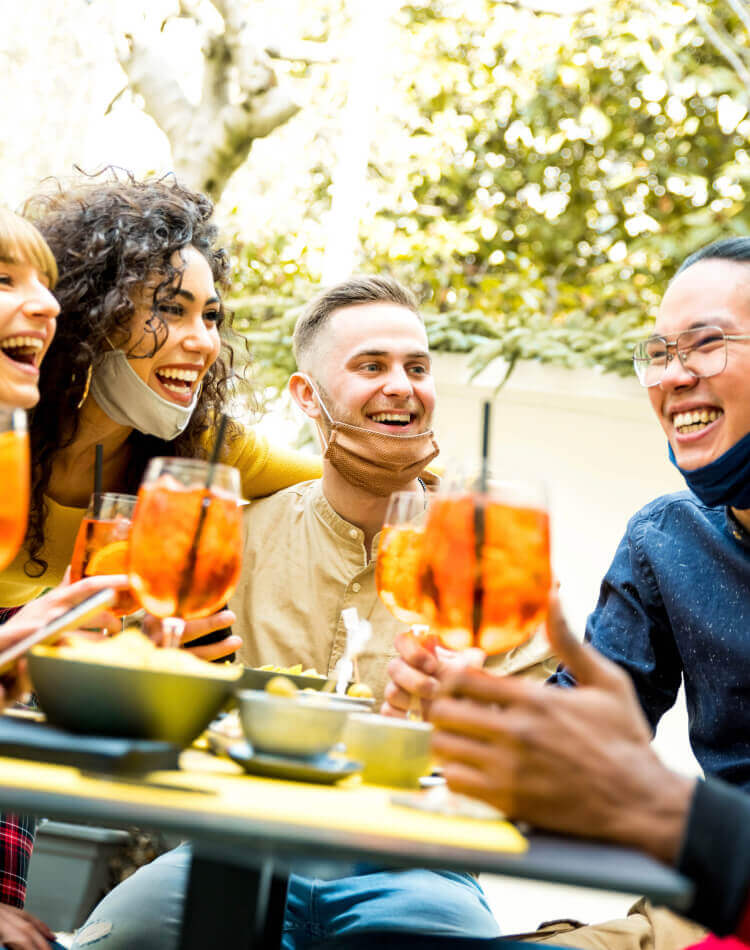 Many people of different ethnicities gathered around a dining table, smiling