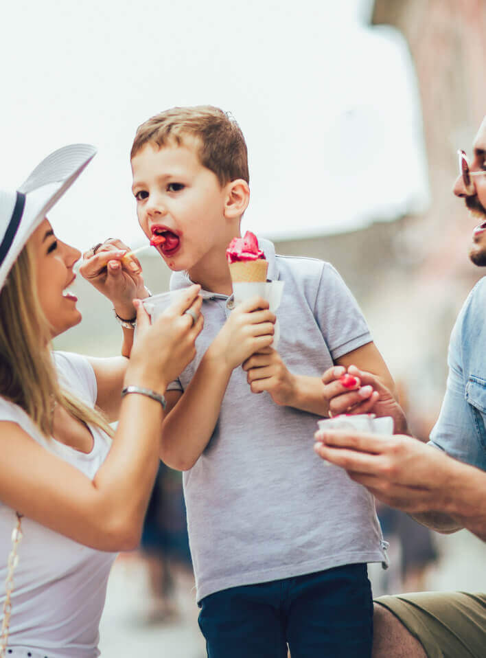 Parents helping a boy eat ice cream